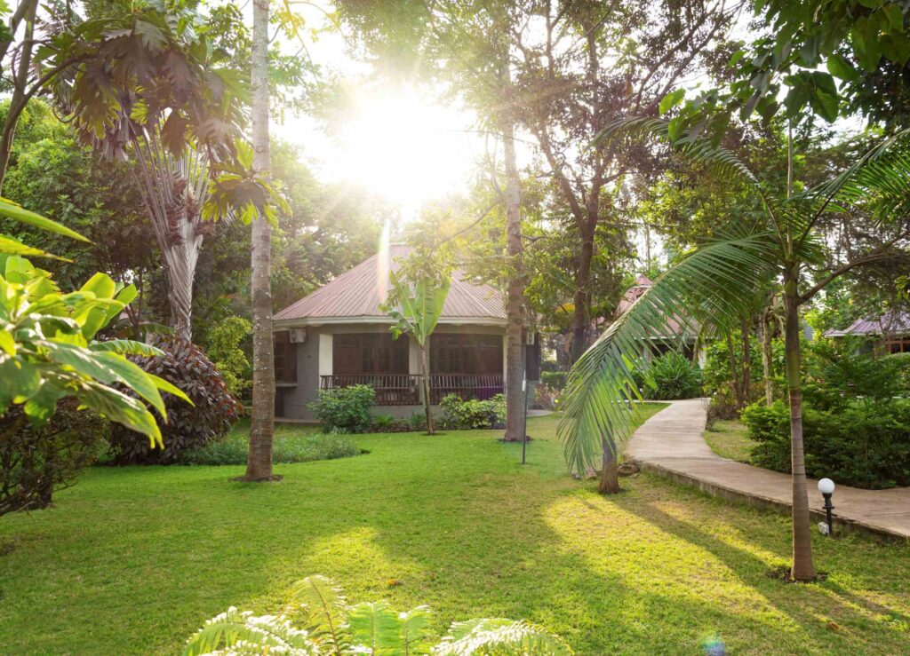 Arusha Planet Lodge i Arusha, hage med runde bungalows, grønn plen og palmetrær