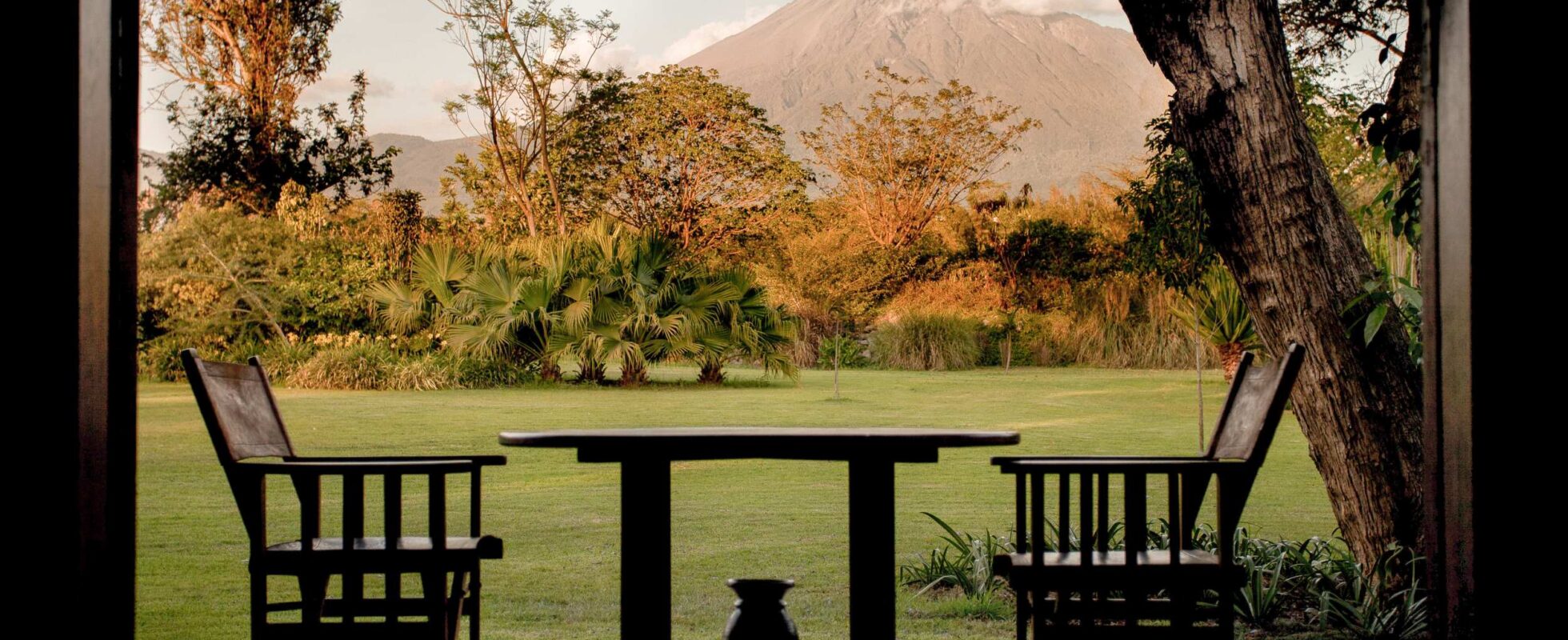 Veranda på Legendary Lodge i Arusha med to stoler og et bord med et fjell i bakgrunnen
