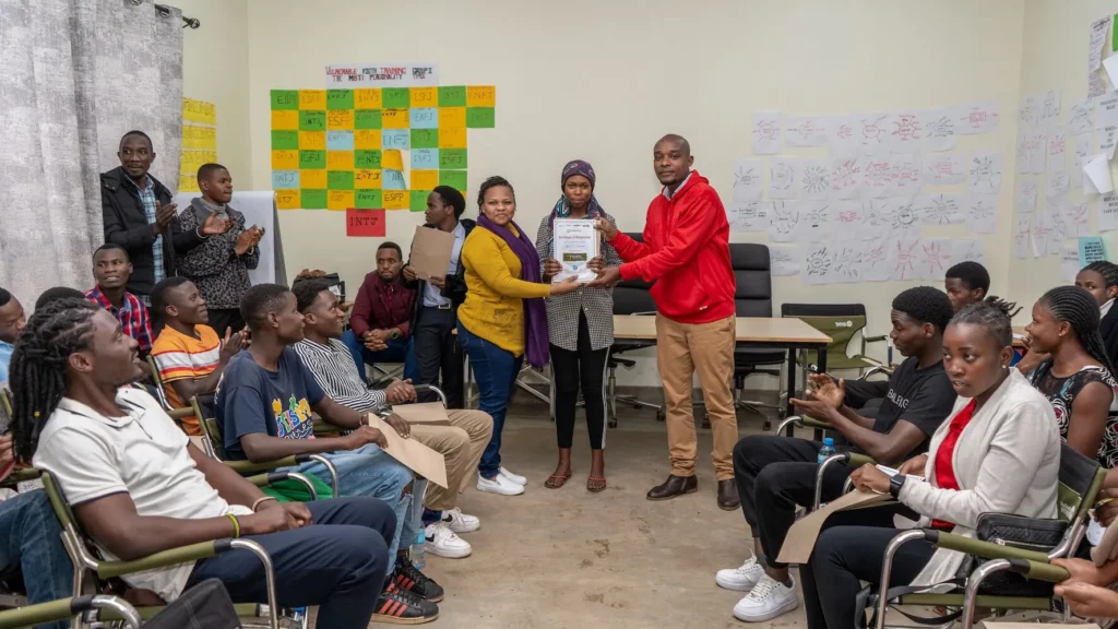 Hakuna Matata Academy. En gruppe elever hvor en mottar en diplom