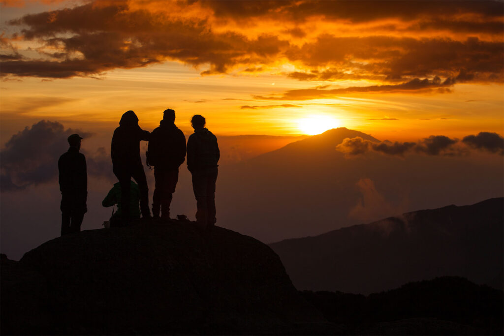 Tre mennesker ser soloppgang på Kilimanjaro