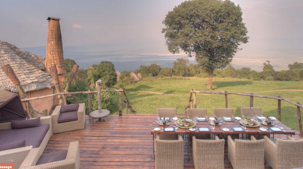 Ngorongoro Crater Lodge terrasse med bord og grønt område i bakgrunnen
