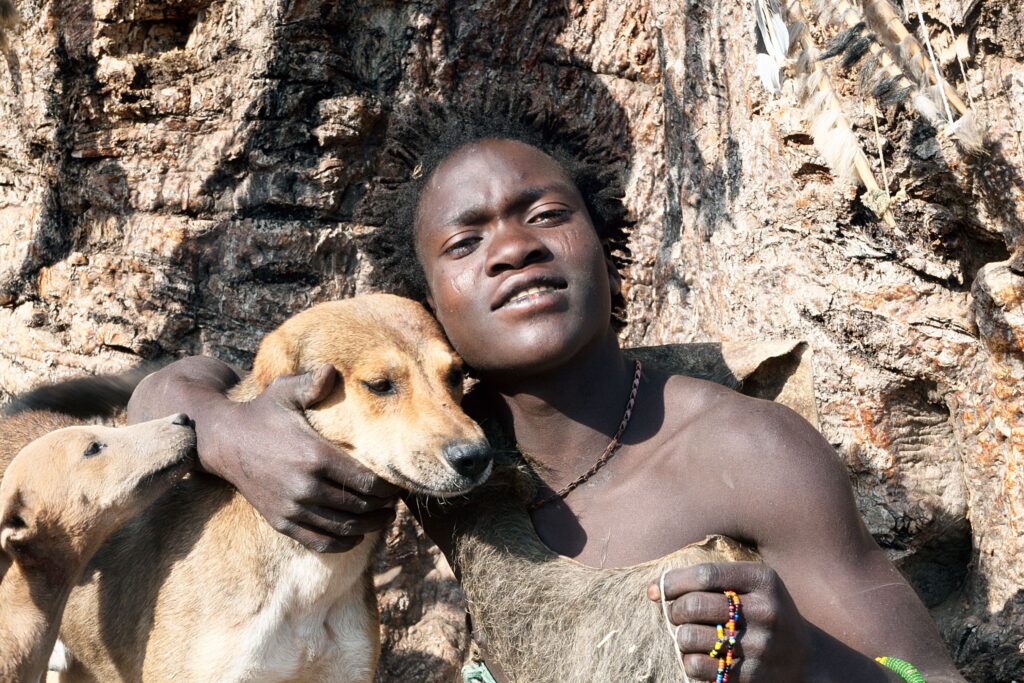 Hvor mange stammer i Tanzania? Mann i tradisjonelle klær med to hunder.