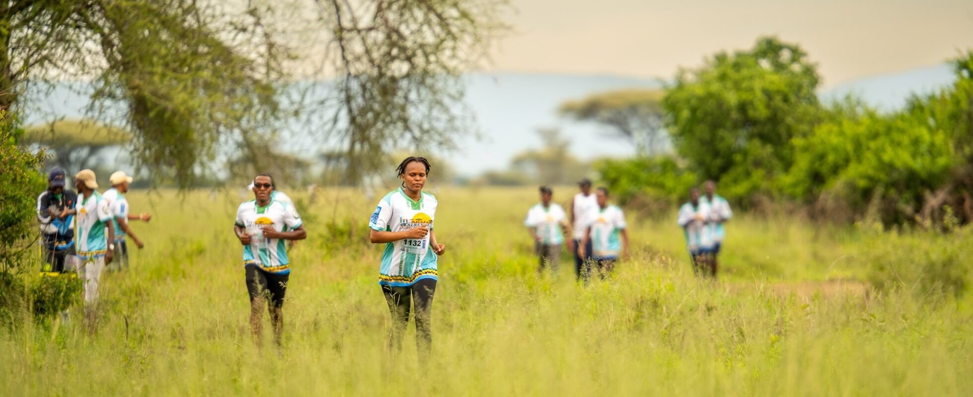 Flere mennesker løper gjennom gresset i Serengeti Marathon 2023