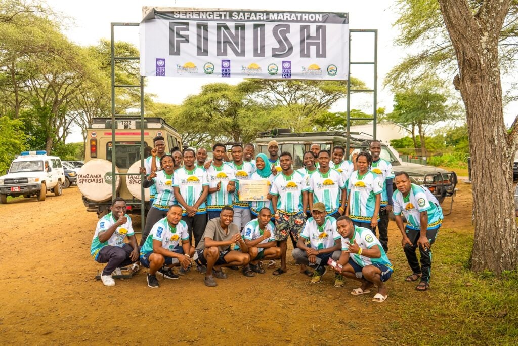Deltakere i Serengeti Marathon 2023 under et skilt som sier "Finish"