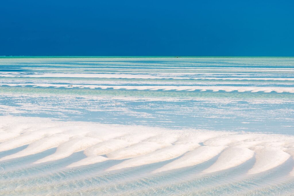 Grunt vann ved Paje, Tanzania, Zanzibar, med bølgende sand