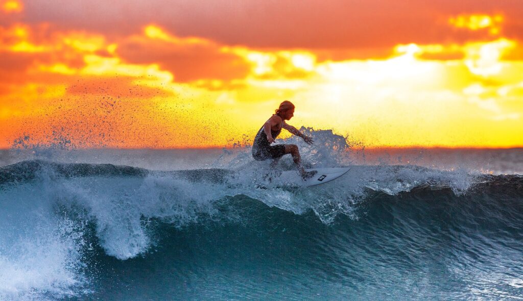 Kvinne surfer i Tanzania på en bølge i solnedgang