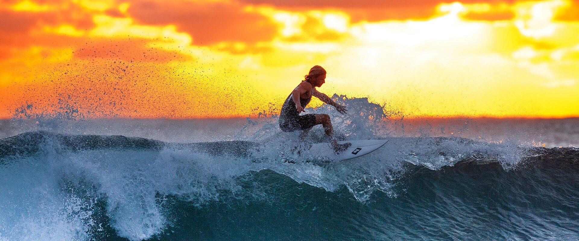 Kvinne surfer i Tanzania på en bølge i solnedgang