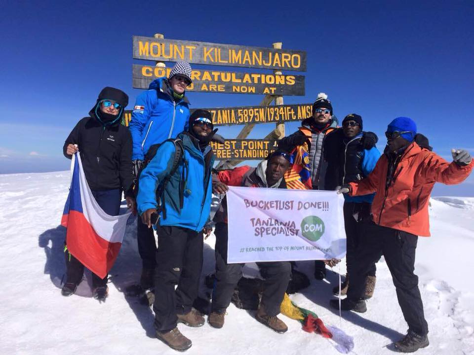 Gruppe mennesker med banner på toppen av Kilimanjaro Tanzania