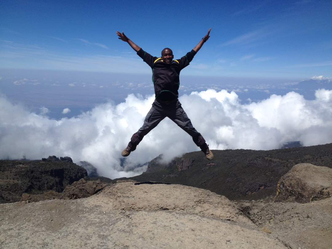 Forberedelser til Kilimanjaro, mann hopper på toppen av Kilimanjaro