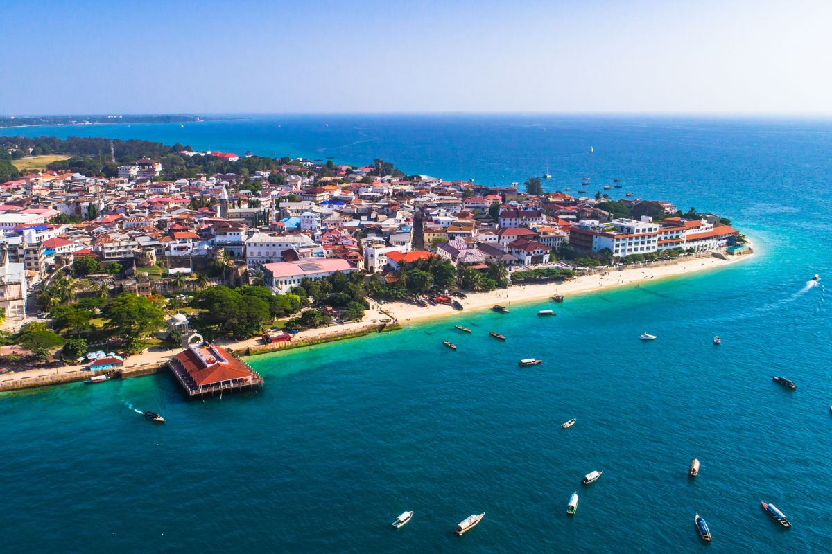 Båter utenfor strandkant ved by sett ovenfra