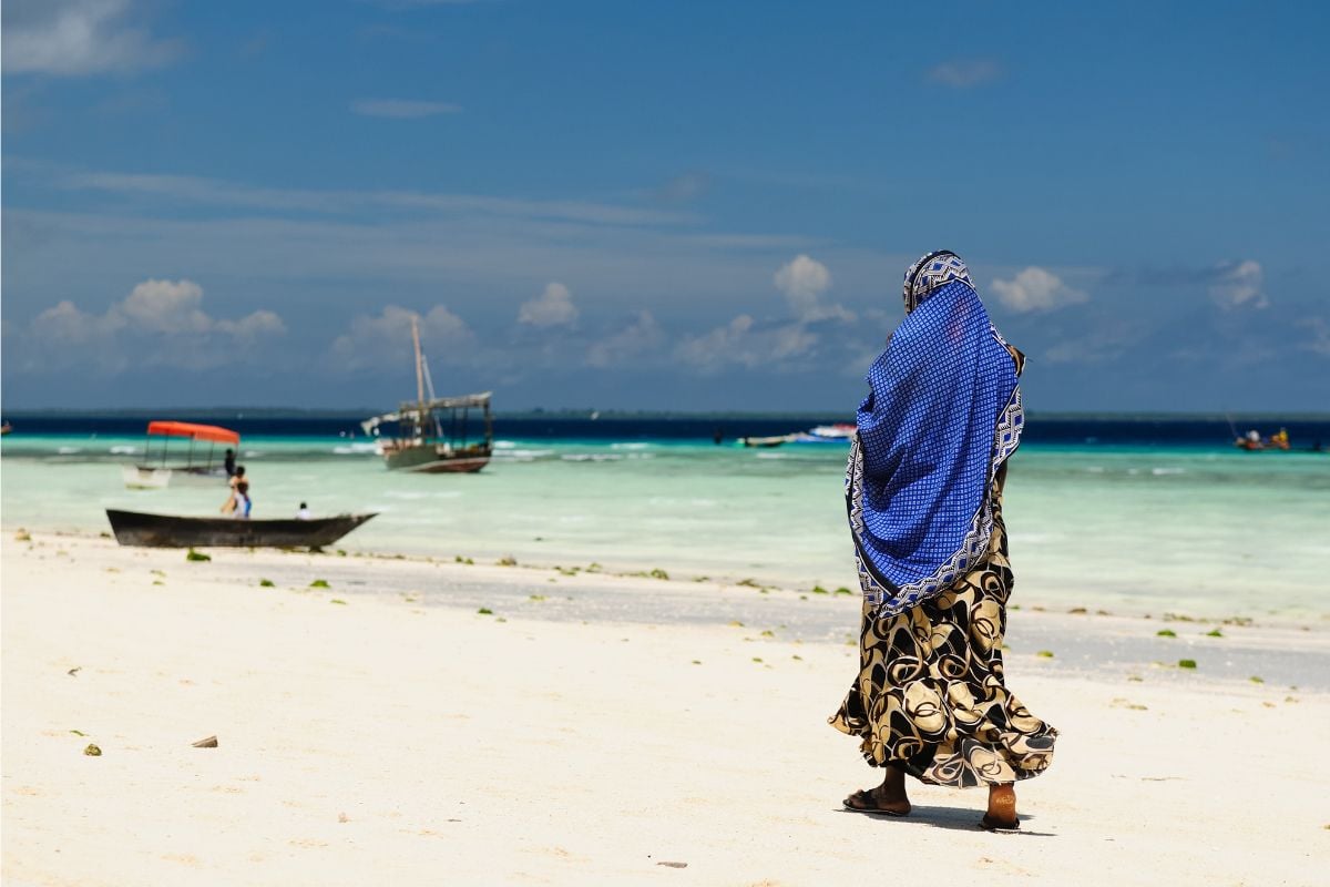 Lokal kvinne går på stranden i Tanzania