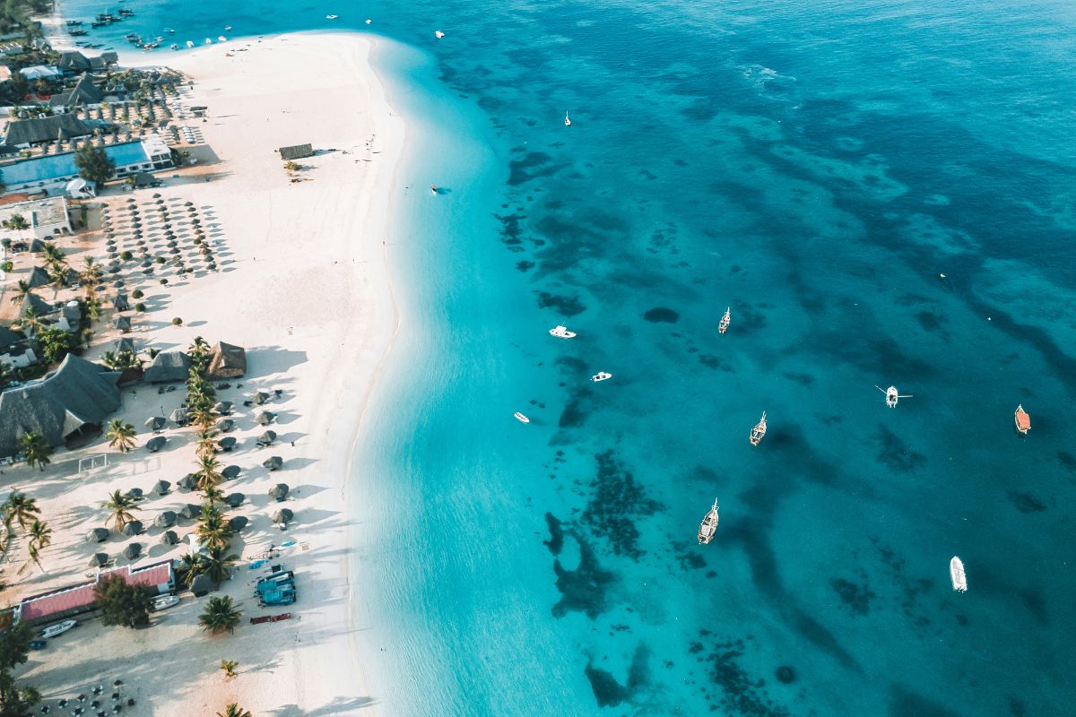 Båter i asurblått hav utenfor hvit sandstrand på Zanzibar